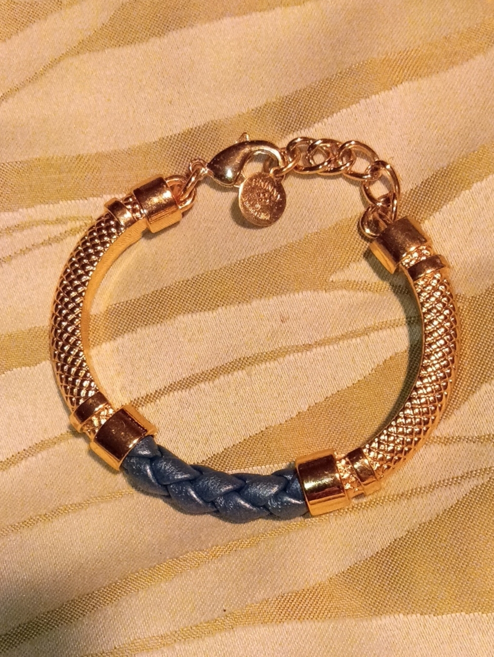 This is a sleek mesh gold tone bracelet with braided leather accents by Jessica